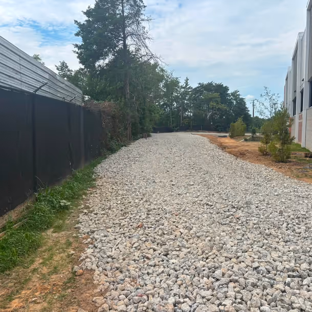 Finished crushed stone access lane graded and spread alongside a commercial building